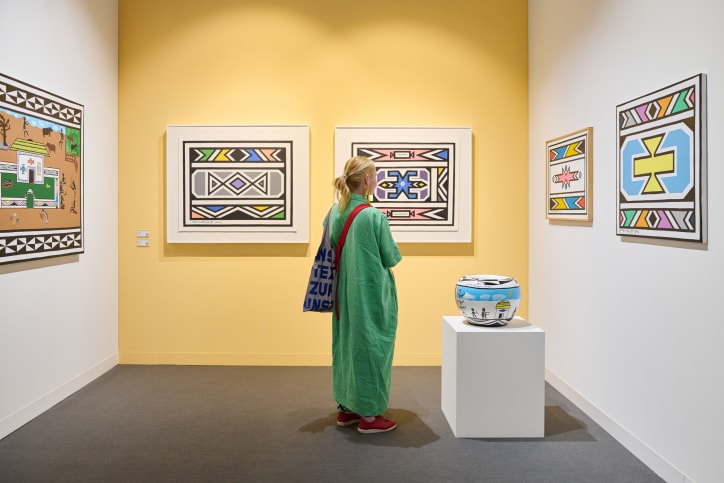 A visitor in the Kabinett section of Jenkins Johnson Gallery, featuring works by Arthur Monroe and Esther Mahlangu at Art Basel in Basel 2025.