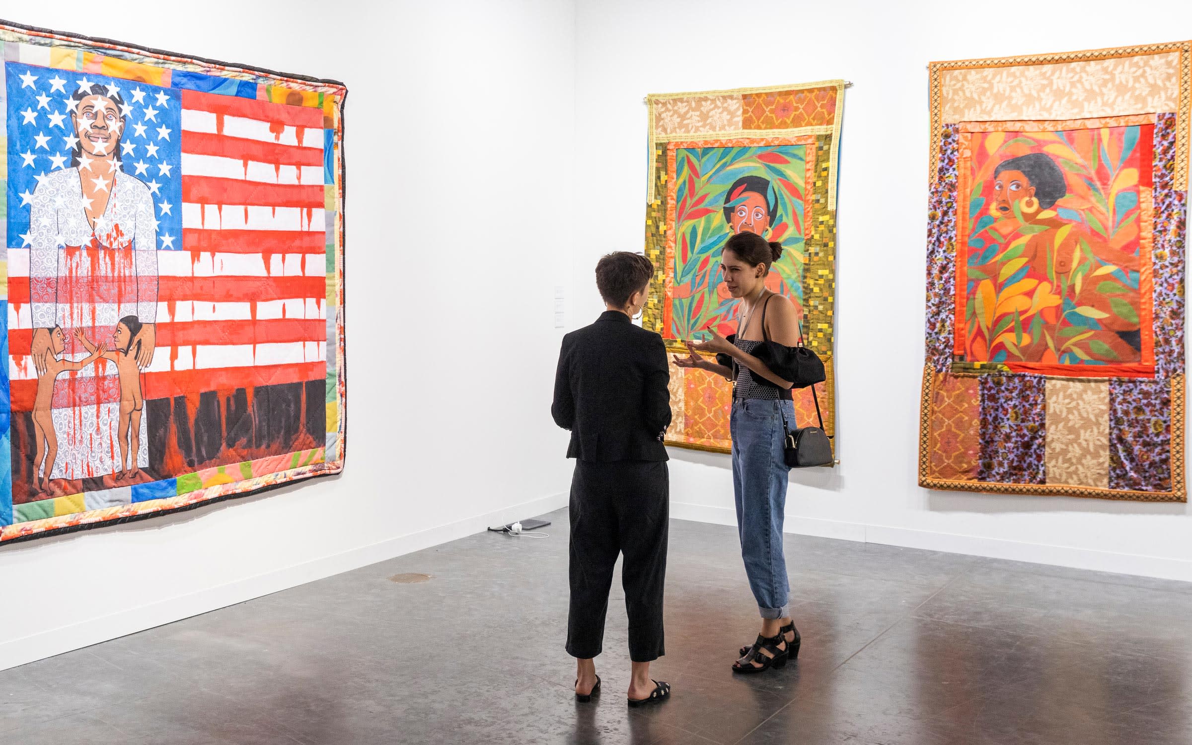 Visitors discussing in front of works by Faith Ringgold, presented in the Survey sector by Pippy Houldsworth Gallery (S2).
