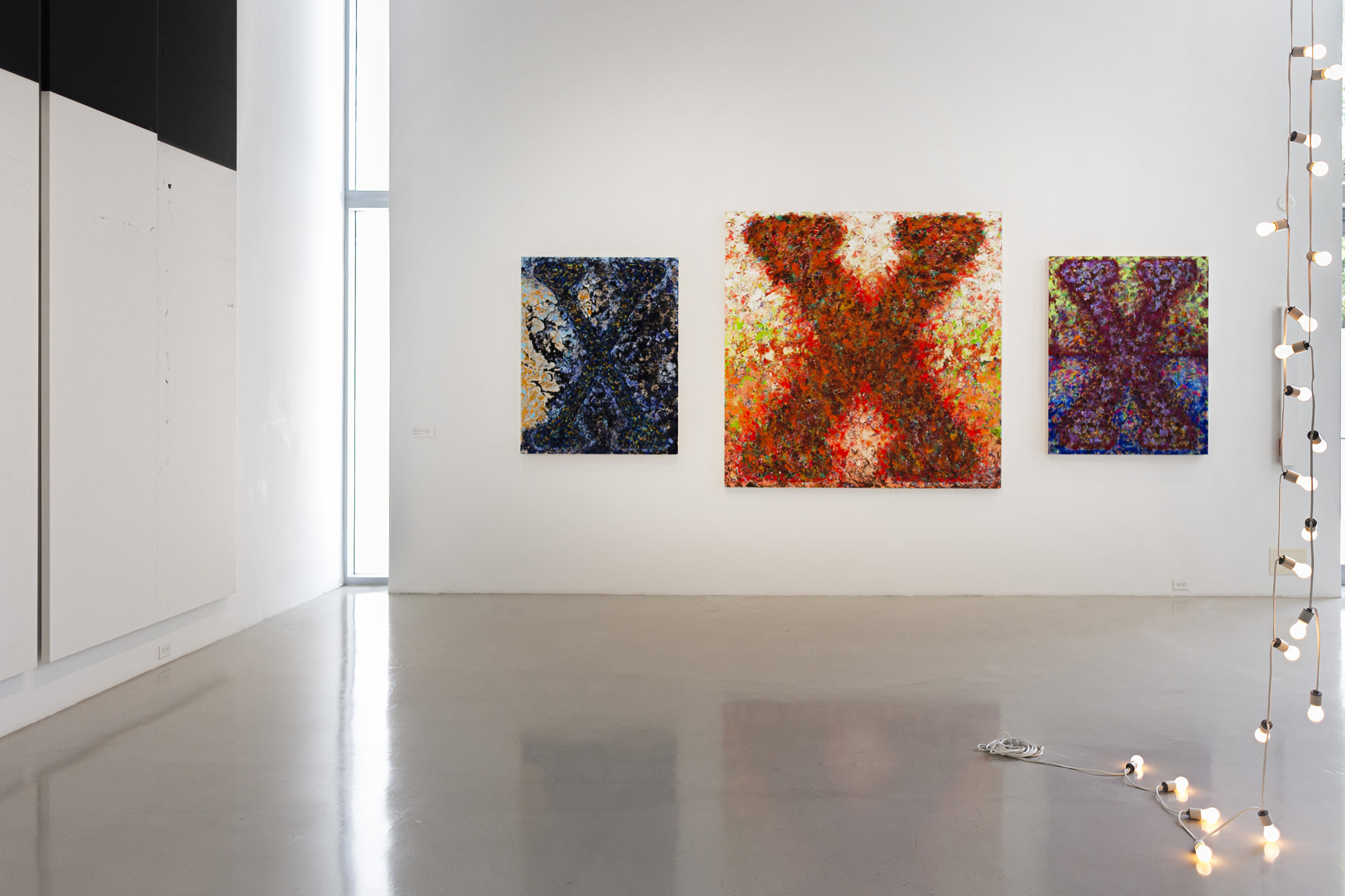 Installation view of 'House in Motion', de la Cruz Collection, 2023–24. Pictured, from left to right: Wade Guyton, Untitled, 2012. Vaughn Spann, Shadow in the Night (Blue Train), 2022; A House on Fire (Marked Man), 2023; and A Love like Dawn, 2022. Felix Gonzalez-Torres, Untitled (America #3), 1992. Courtesy of the de la Cruz Collection.