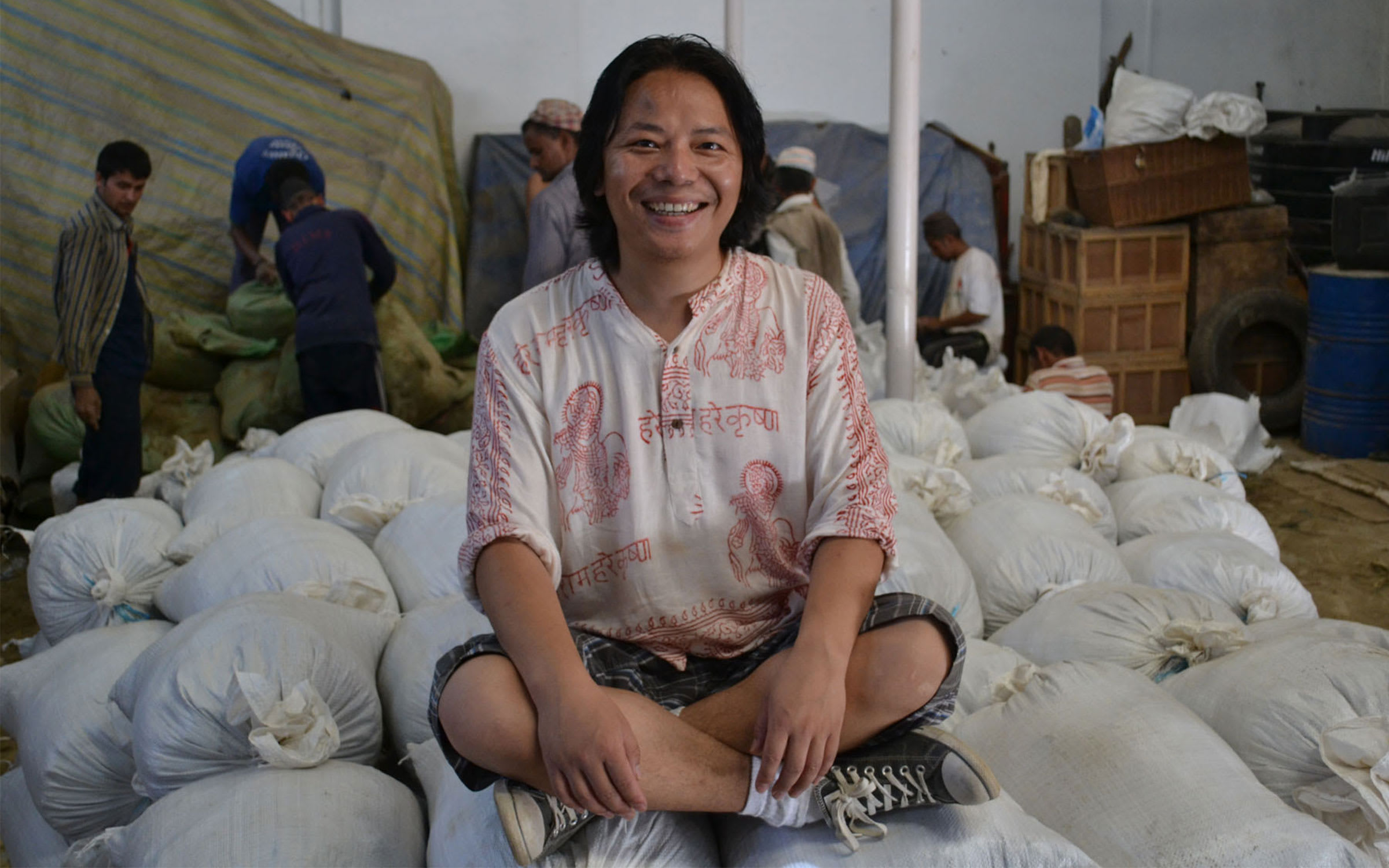 Tenzing Rigdol sitting on bags of soil, sourced as part of his 2011 work Our People, Our Land. Courtesy of the artist and Rossi 6 Rossi, Hong Kong.