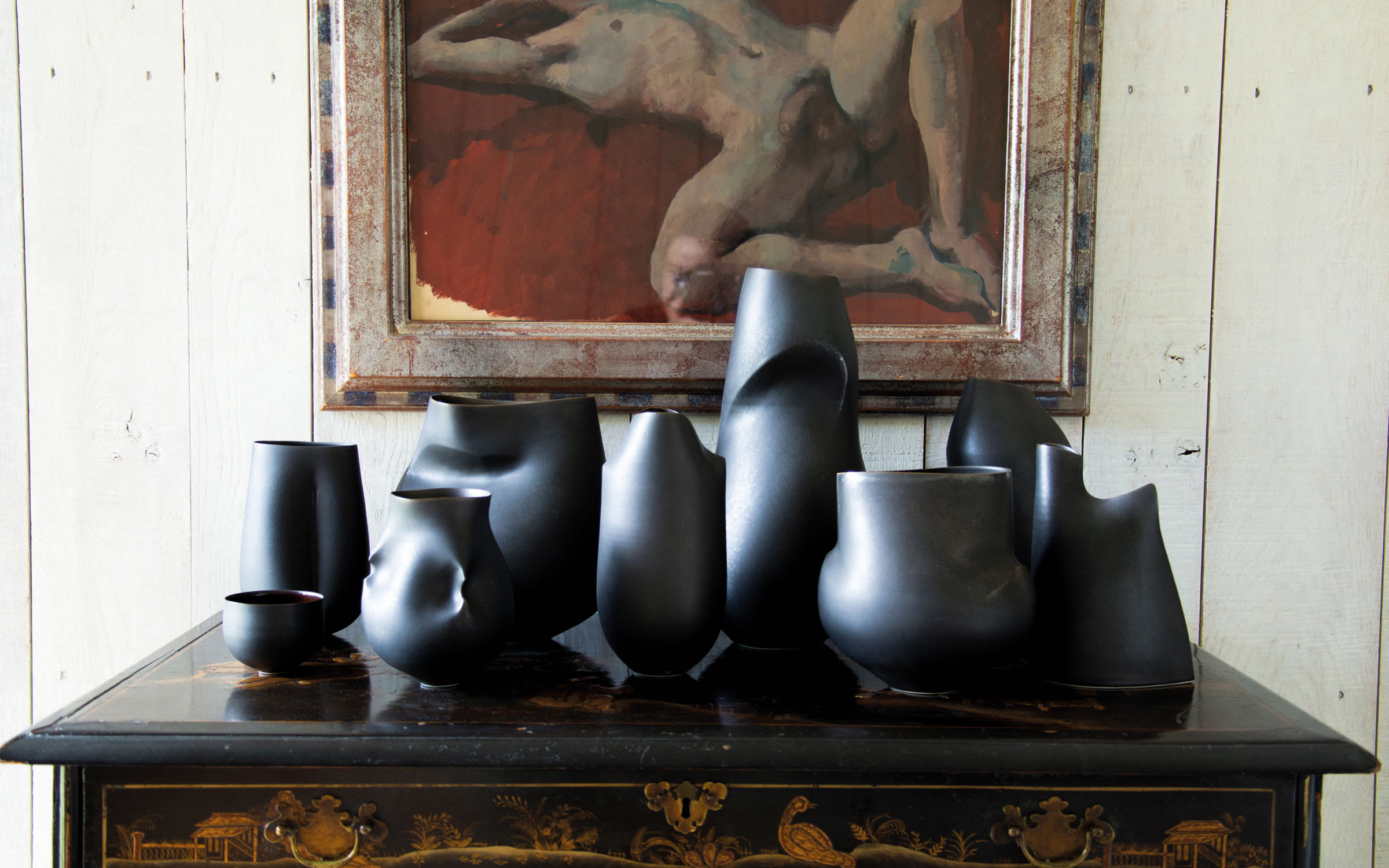 In the foreground, a series of ceramics by Sarah Flynn; in the background, a detail of Robert Petit reclining with red background, by Pavel Tchelitchew.